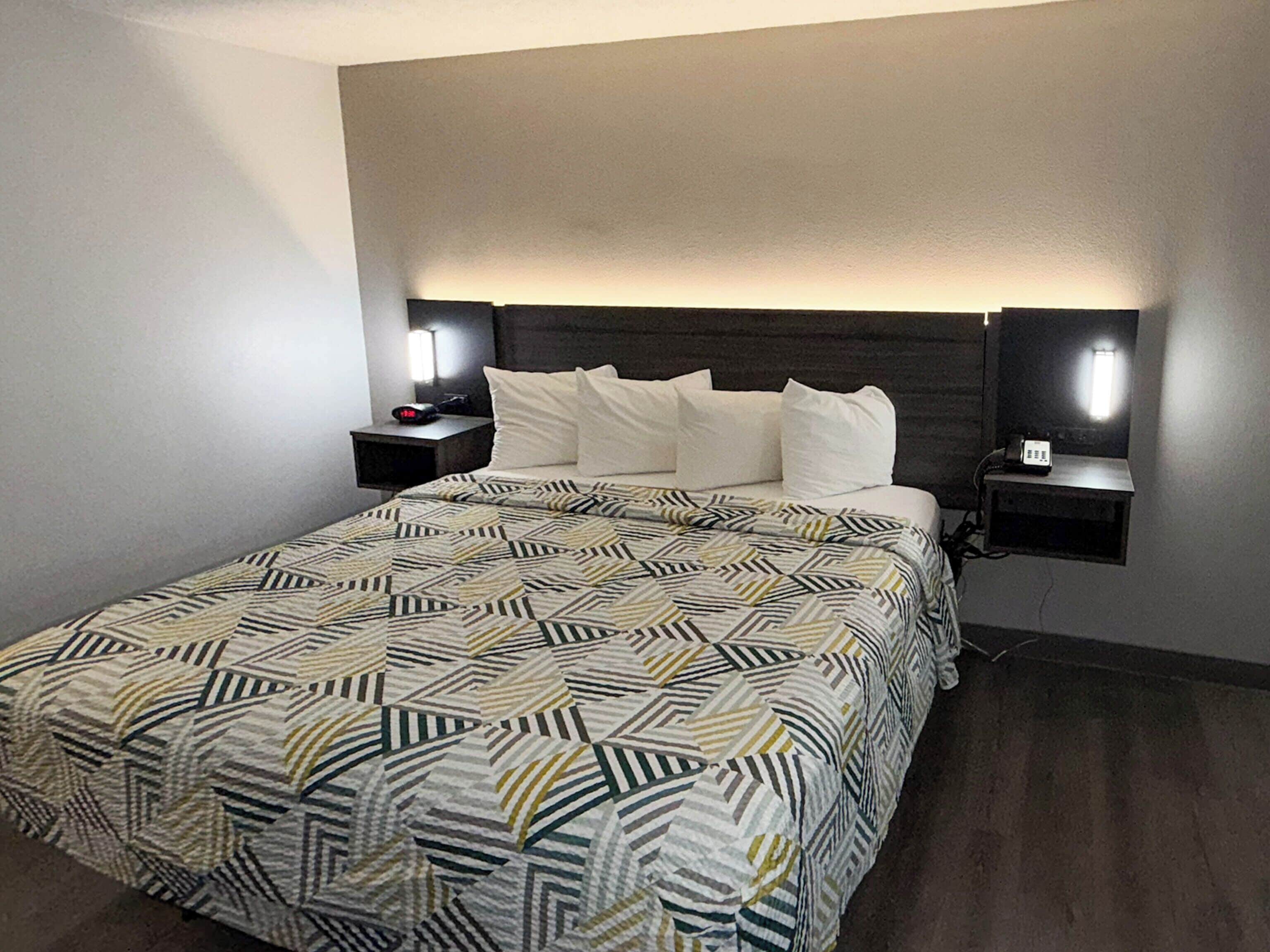 Ein Hotelzimmer mit Bett, zwei Nachttischen und einem Kopfteil.