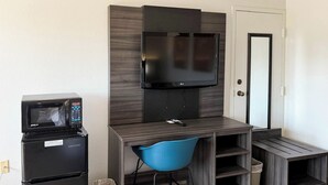 A compact room with a kitchenette, a flat-screen TV, a blue chair, and a small desk. - Motel 6 Stafford, VA - Quantico (Stafford)