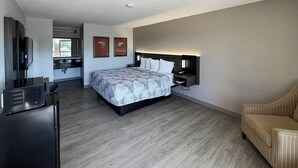 A modern hotel room with a large bed, a desk, a television, and a sofa. - Motel 6 Stafford, VA - Quantico (Stafford)