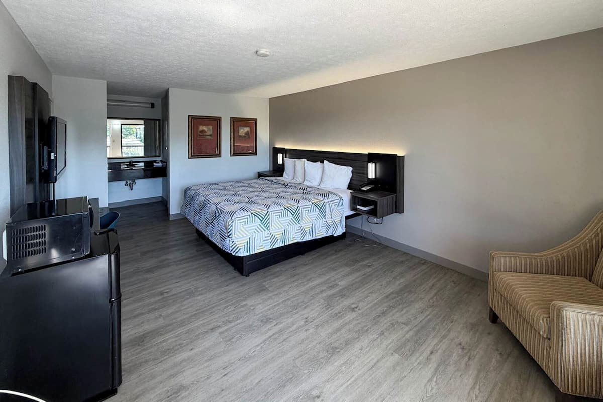 A modern hotel room with a large bed, a desk, a television, and a sofa.