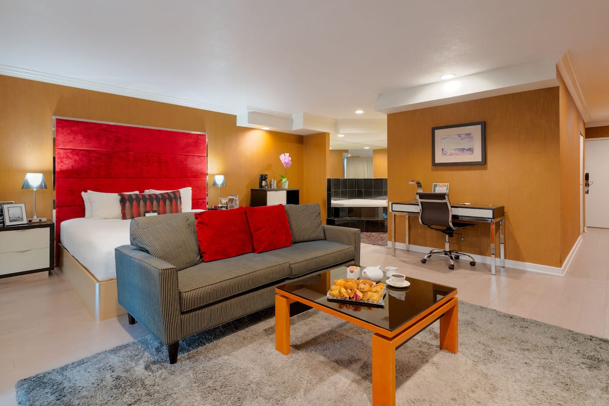 A hotel room with a bed, a sofa, a desk, and a coffee table.