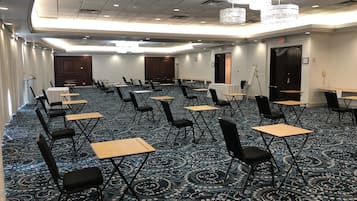 A conference room with rows of tables and chairs, a patterned carpet, and a chandelier.