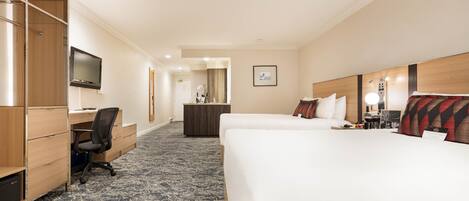 A hotel room with a bed, desk, chair, TV, and a small bathroom area.