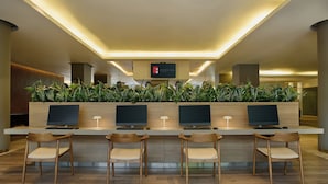 A modern reception desk with multiple computer monitors, a flat-screen TV, and a plant display. - Fiesta Inn Monterrey Valle (San Pedro Garza García)