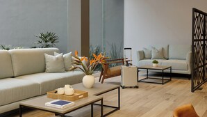 A modern living room with a sofa, coffee table, and decorative plants. - Fiesta Inn Monterrey Valle (San Pedro Garza García)