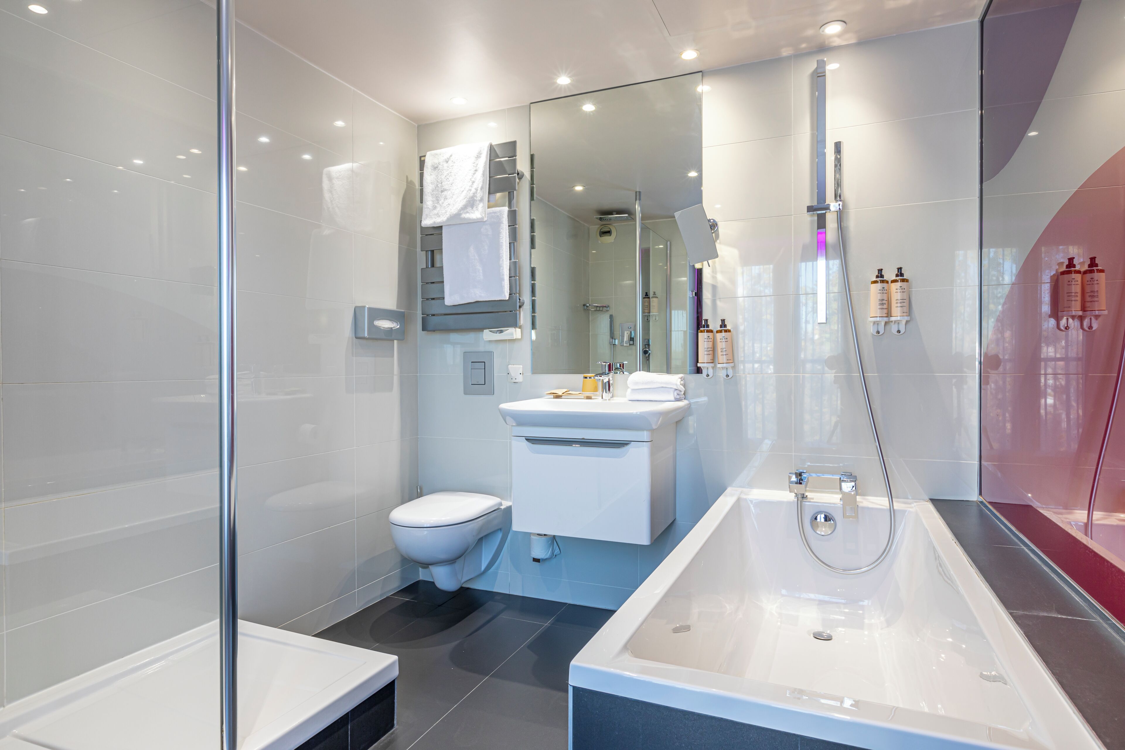 Un baño moderno con cabina de ducha de vidrio, inodoro blanco y una bañera grande.