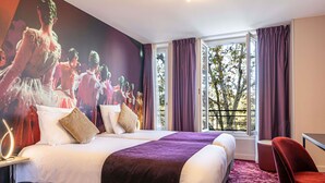 Quarto de hotel com uma cama grande, uma mesa, uma cadeira e uma janela com cortinas.
