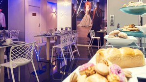 Um saguão moderno de hotel com área de estar, buffet de pastéis e vista para uma pessoa vestida.