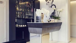 Uma área de bar moderna com bancada preta elegante, uma vitrine de vidro com garrafas e um arranjo decorativo de orquídeas.