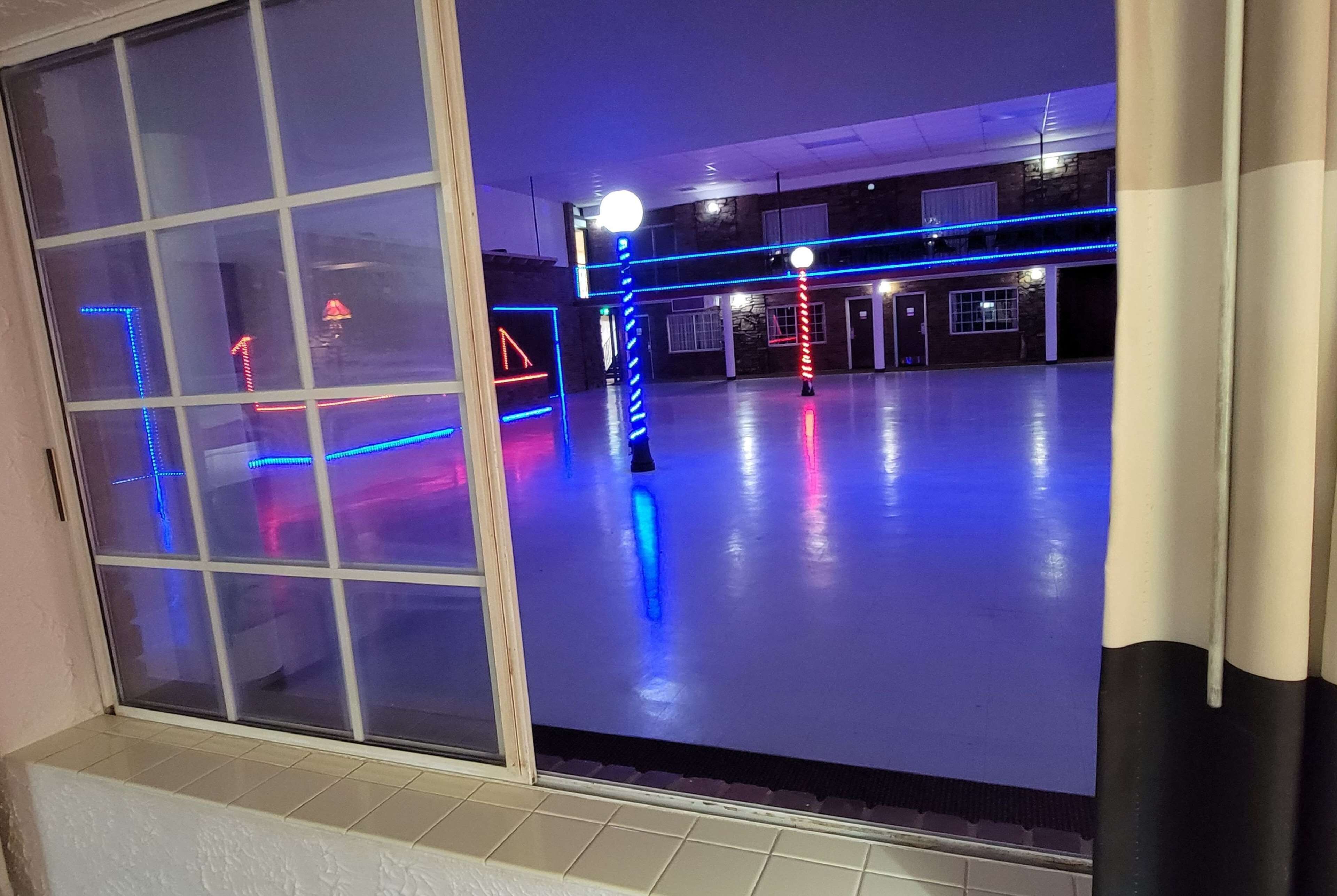A spacious indoor area with a polished floor and blue and red neon lights.