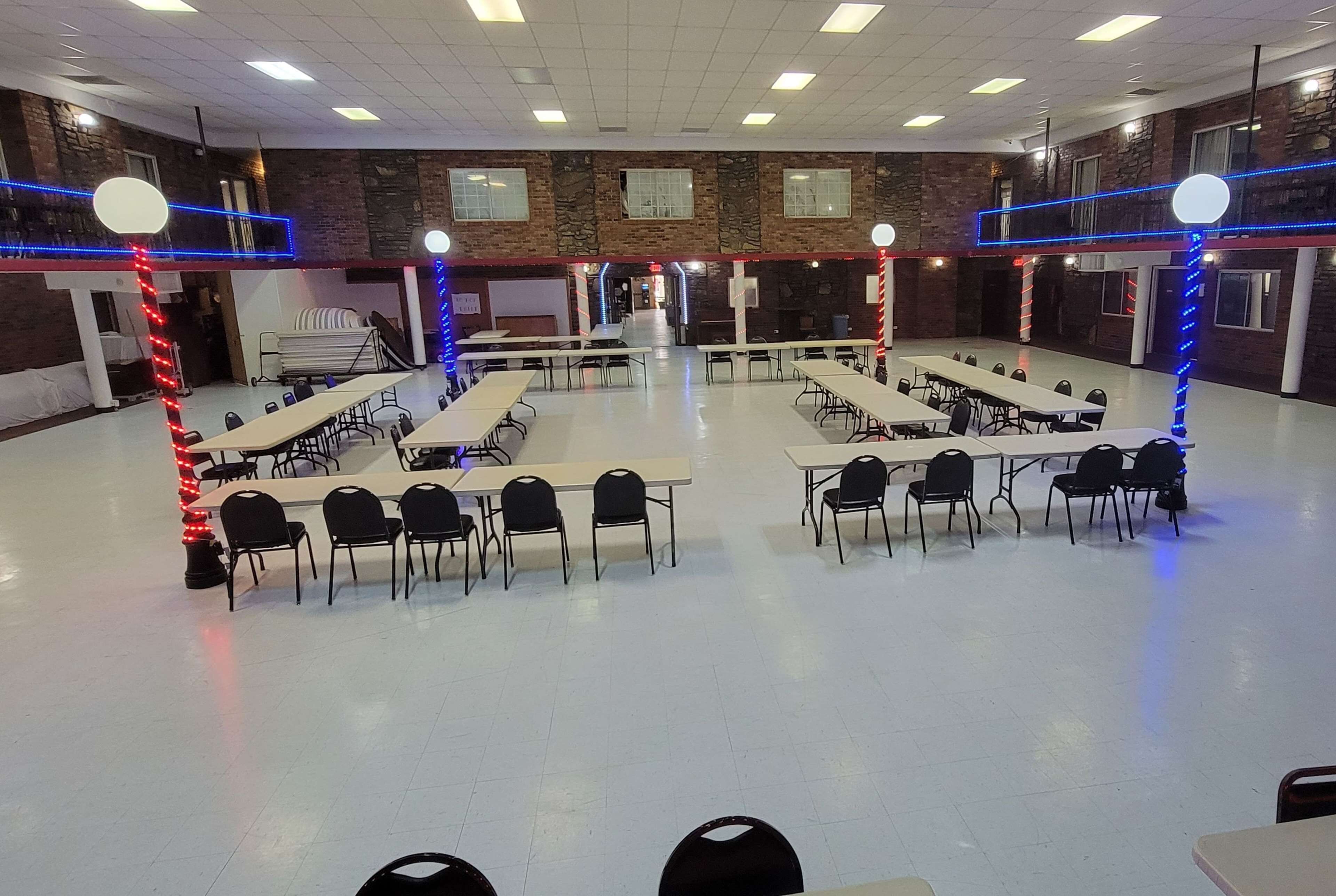 A large, well-lit conference room with multiple tables and chairs, high ceilings, and brick walls.