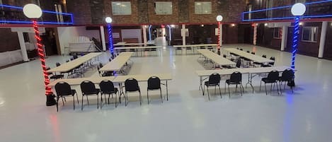A large, well-lit conference room with multiple tables and chairs, high ceilings, and brick walls.