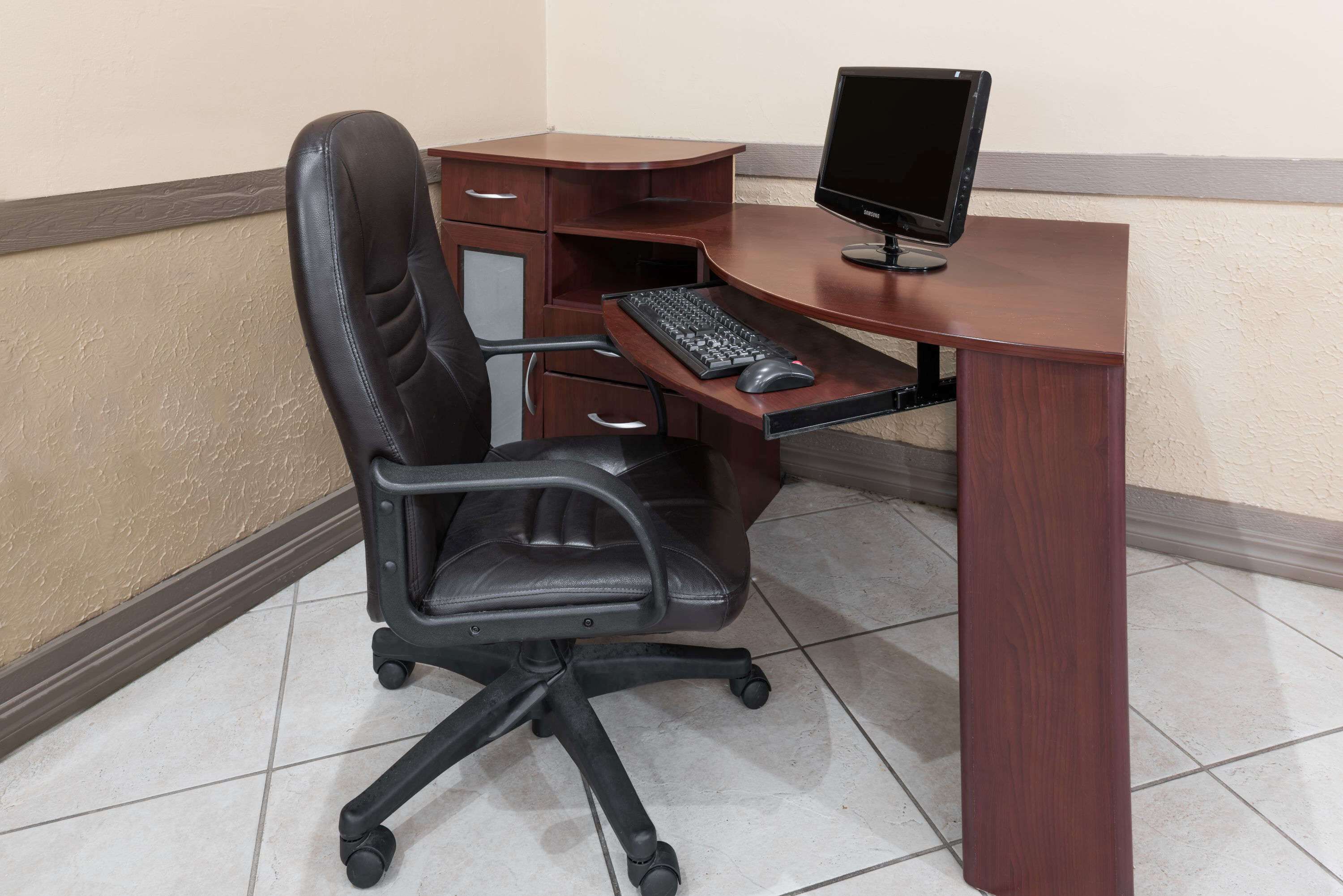A corner office setup with a desk, chair, computer, and keyboard.