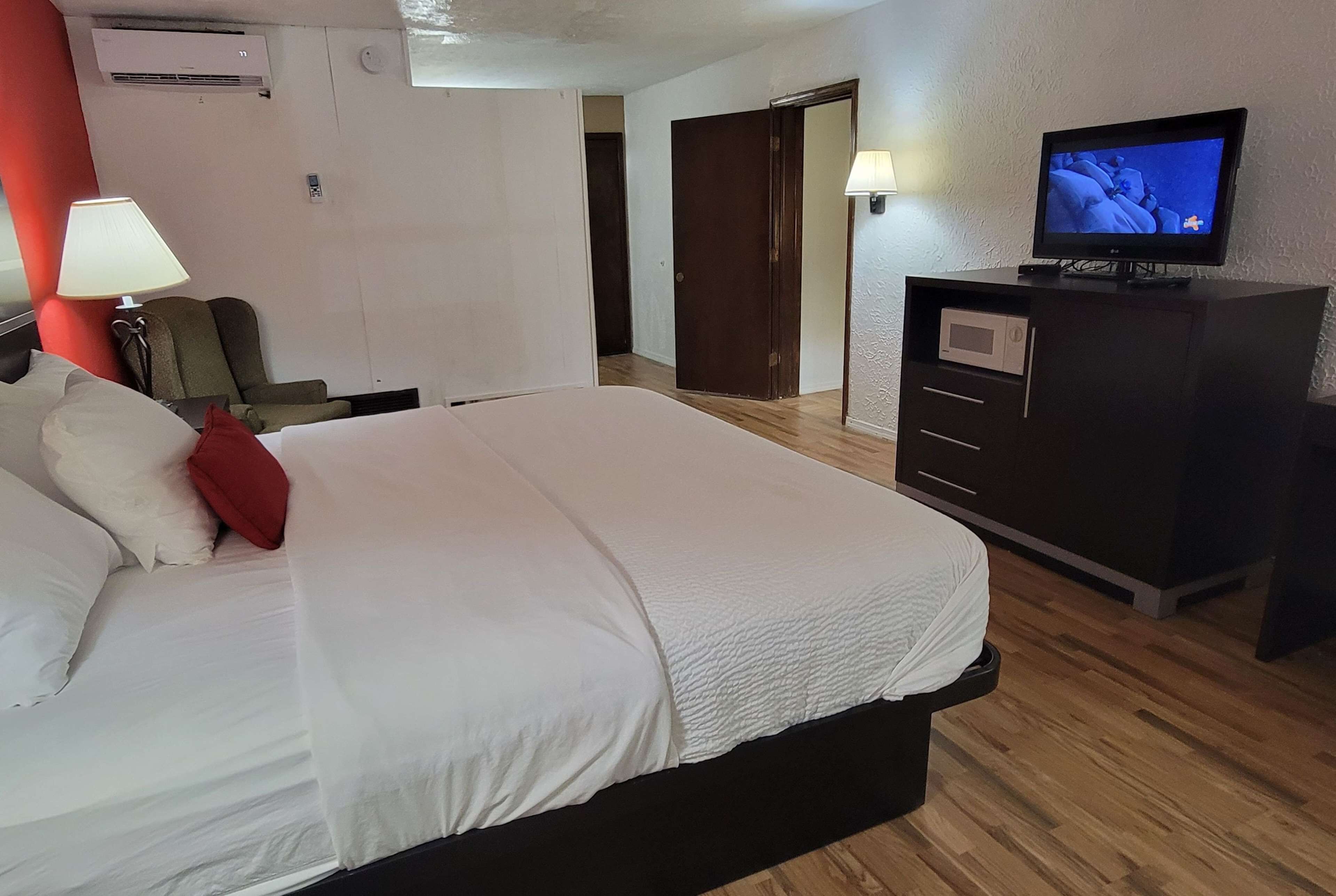 A hotel room with a bed, a TV, a desk, and a lamp.