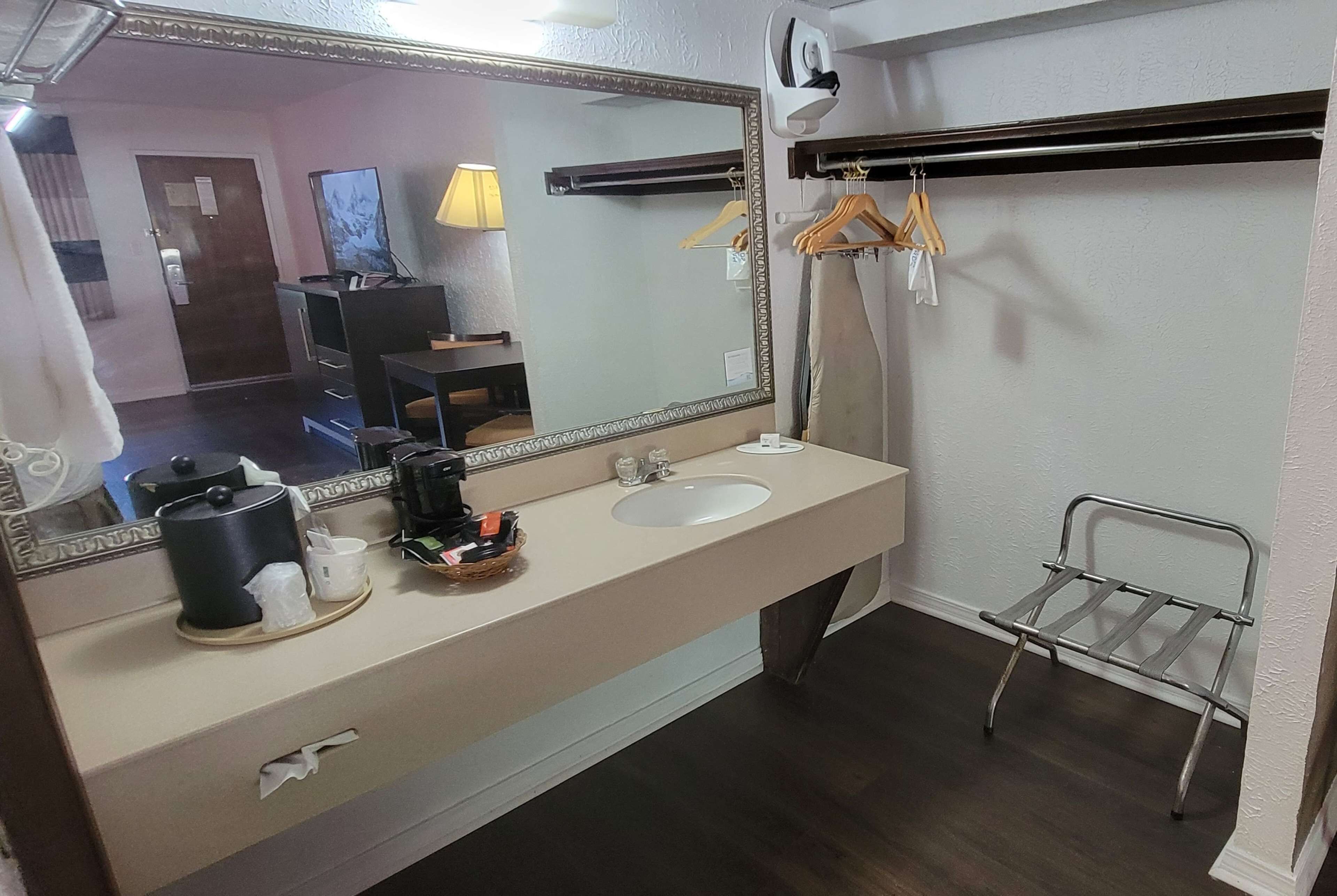 A bathroom with a large mirror, two sinks, a towel rack, and a metal chair.