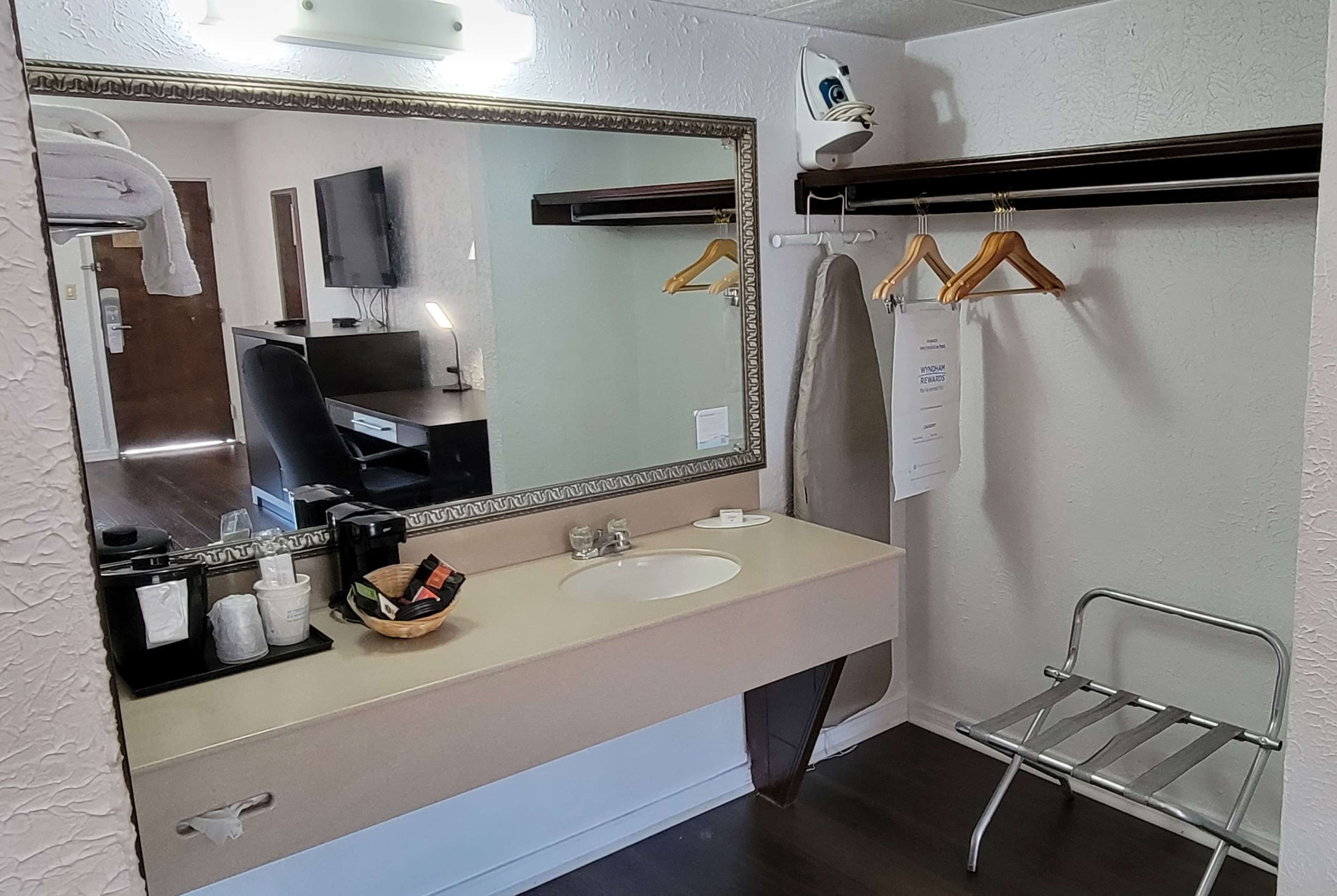 Un baño con un espejo grande, dos lavamanos, un secador de pelo y un perchero para toallas.