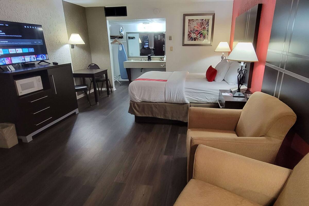 A hotel room with a bed, a desk, a TV, and a chair.