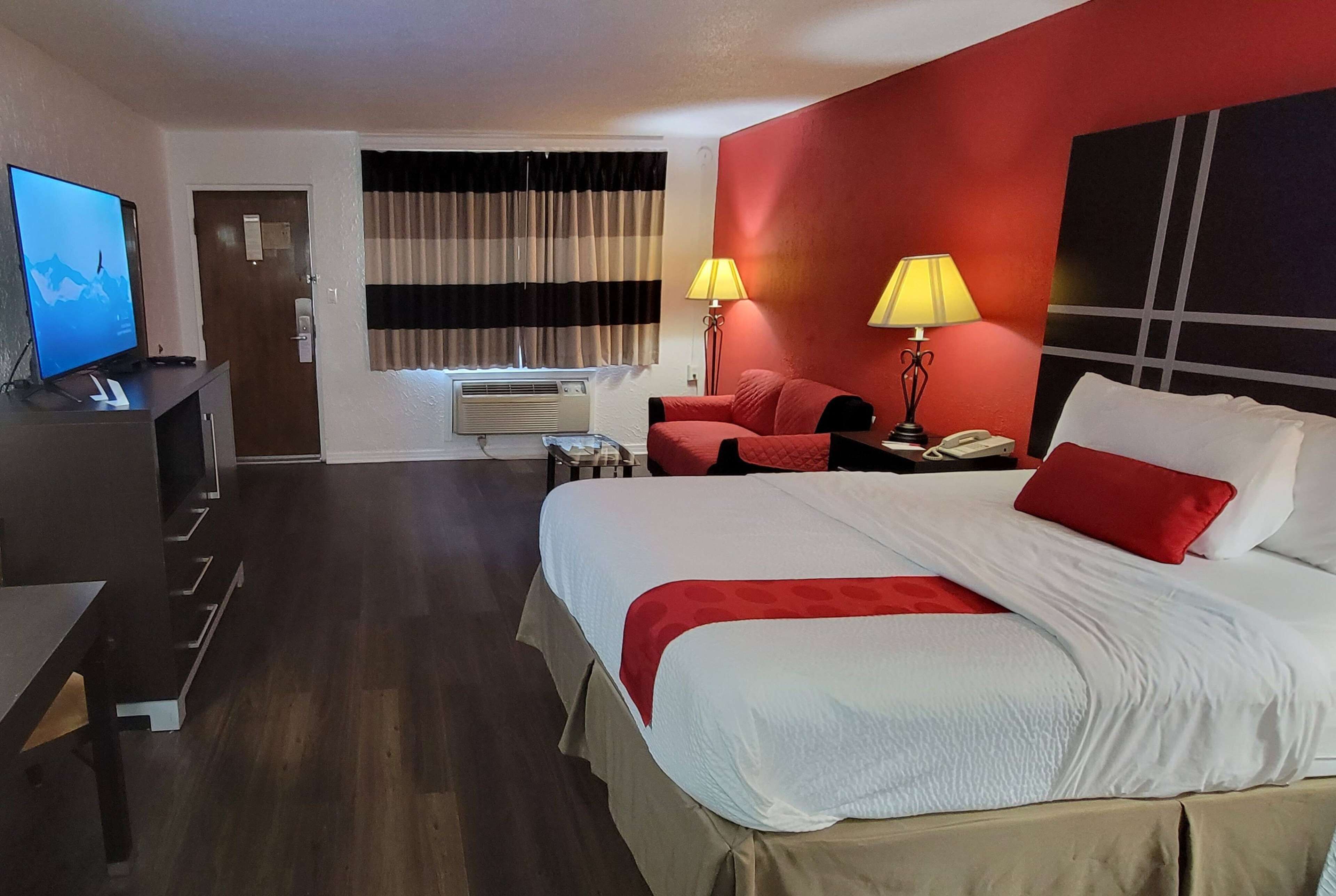 Una habitación de hotel con una cama grande, televisión, escritorio y silla.