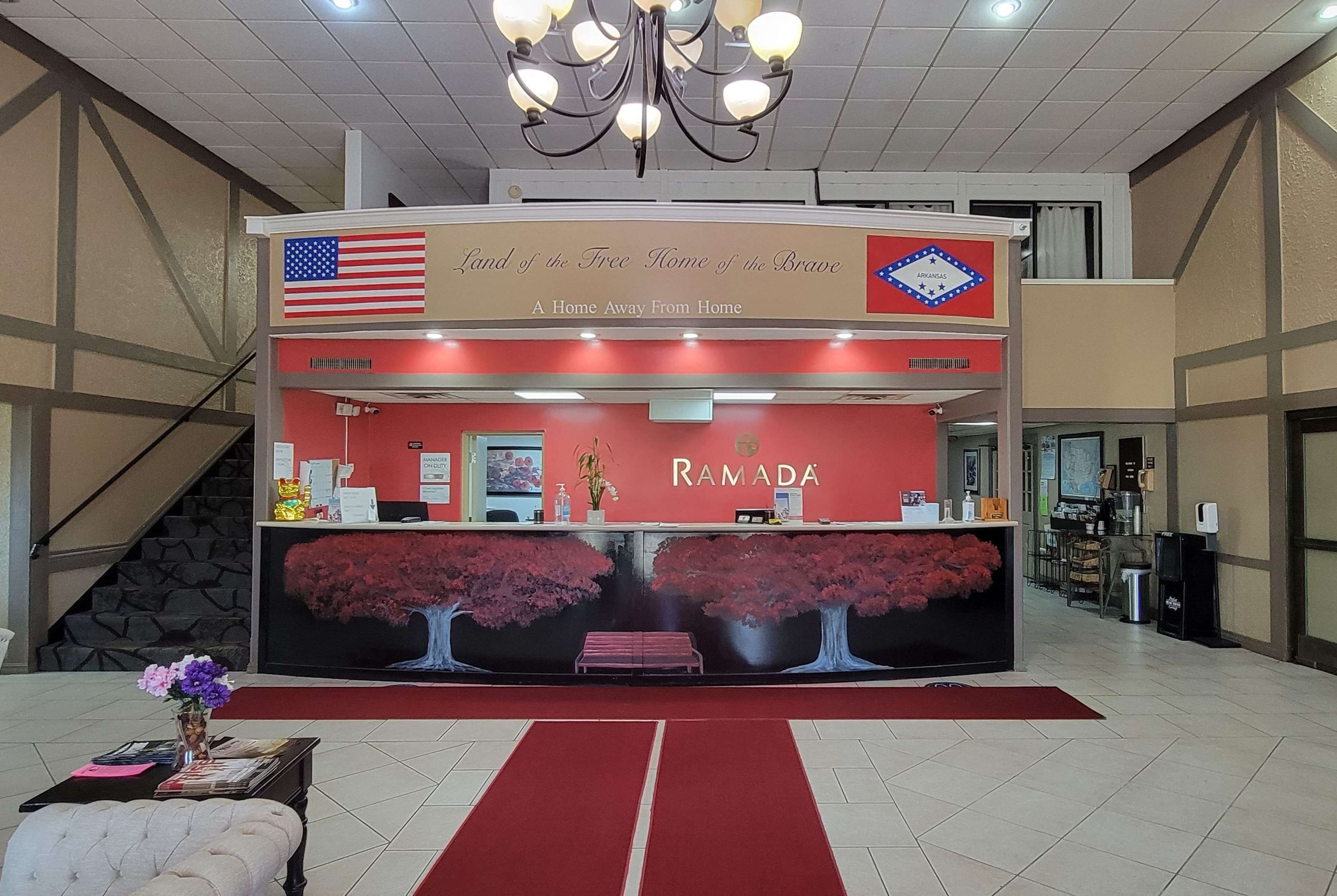 A reception area with a red carpet, a chandelier, and a sign reading "Land of the Free Home of the Brave".