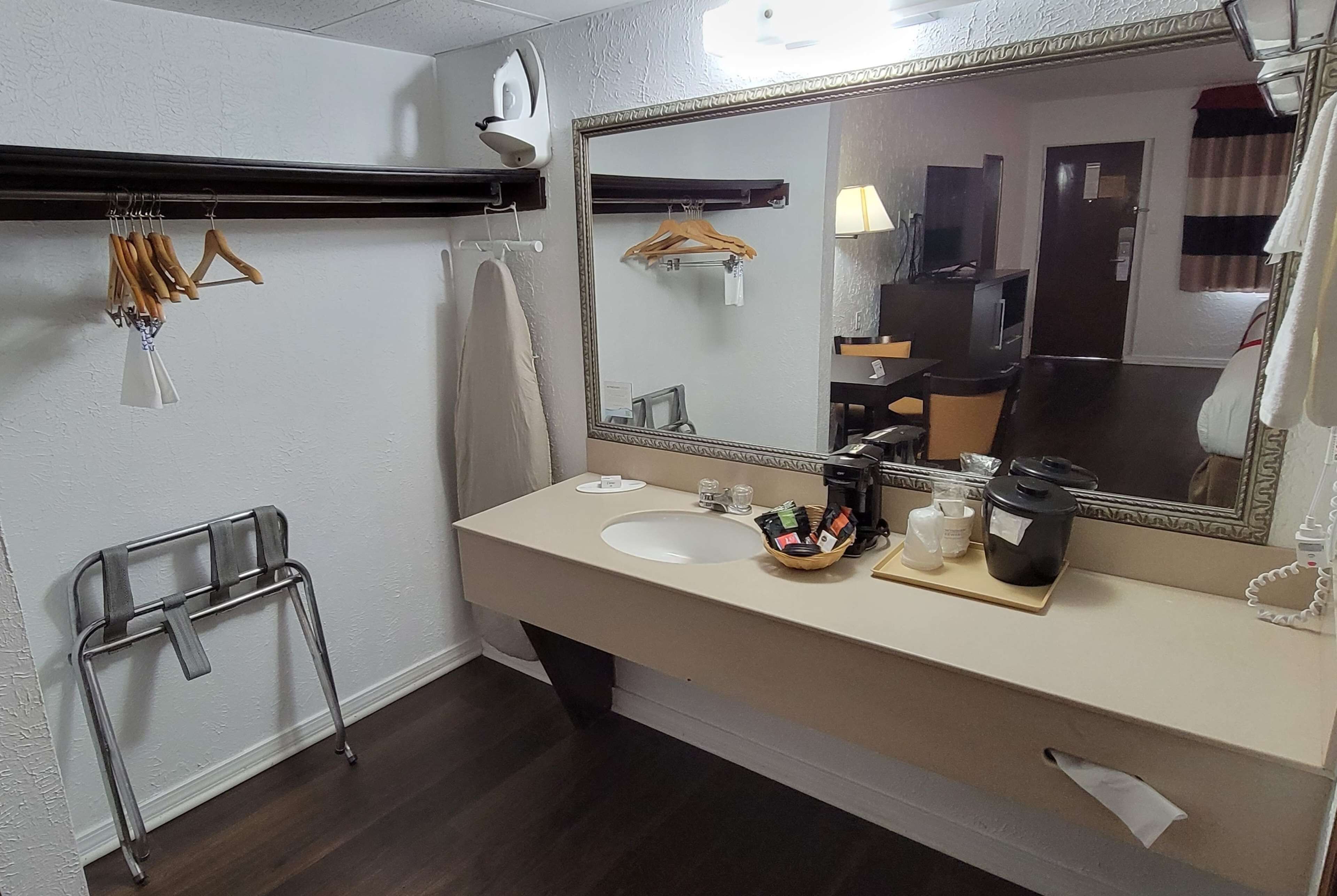 Un baño con lavamanos, espejo, perchero para ropa y toallero.