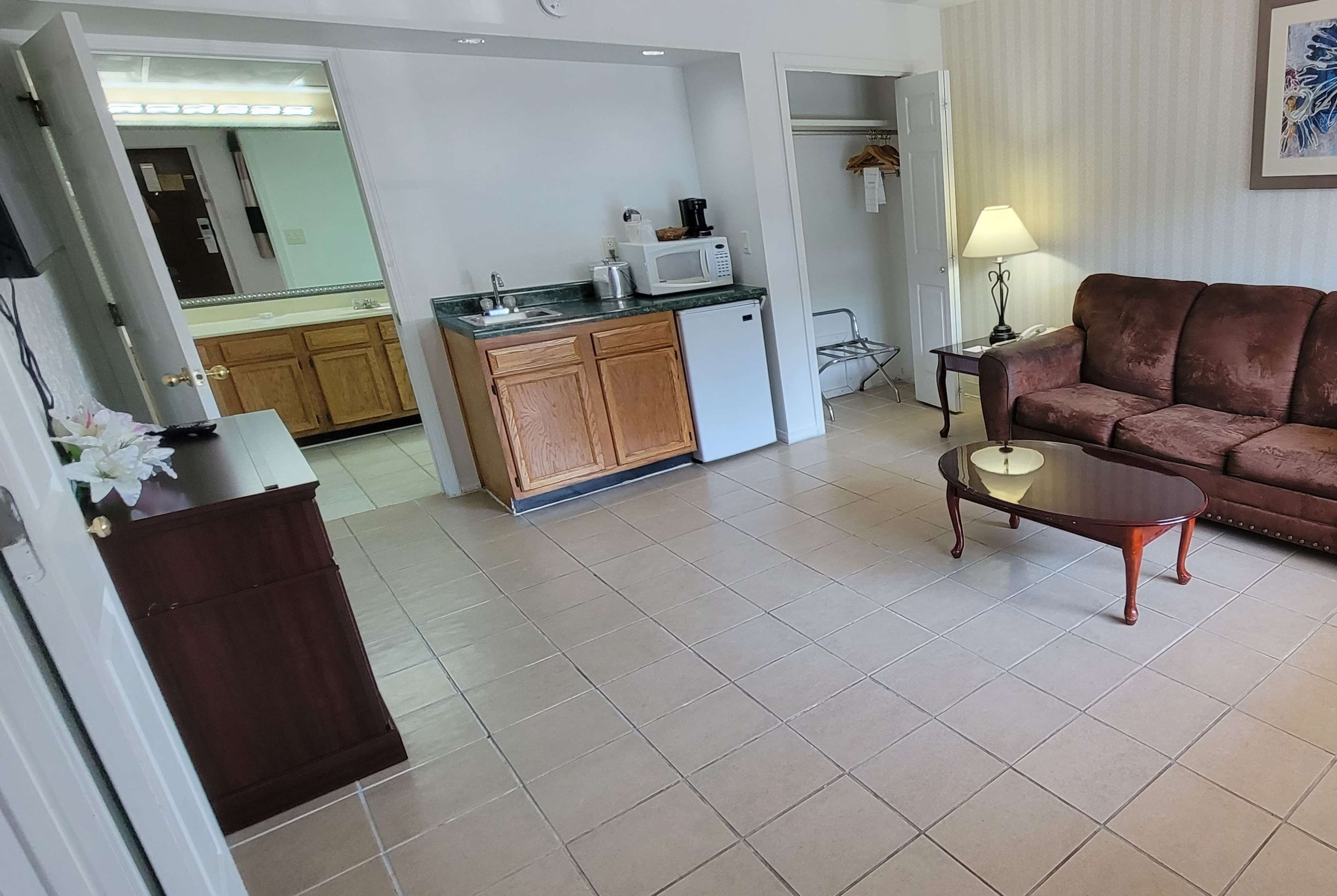 A compact living space with a kitchenette, a brown leather sofa, and a glass coffee table.