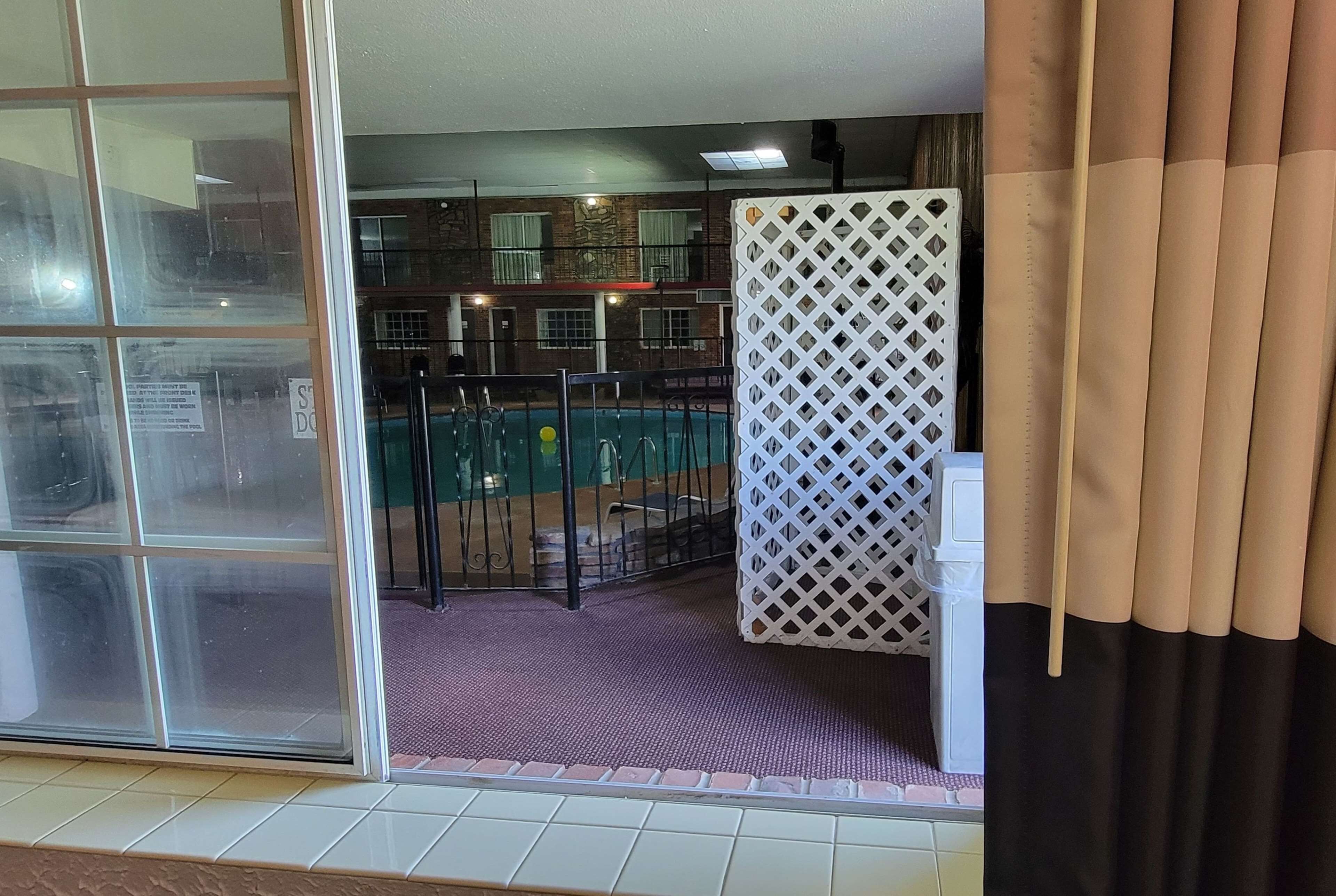 A room with a view of a pool, a white lattice partition, and a sliding glass door.