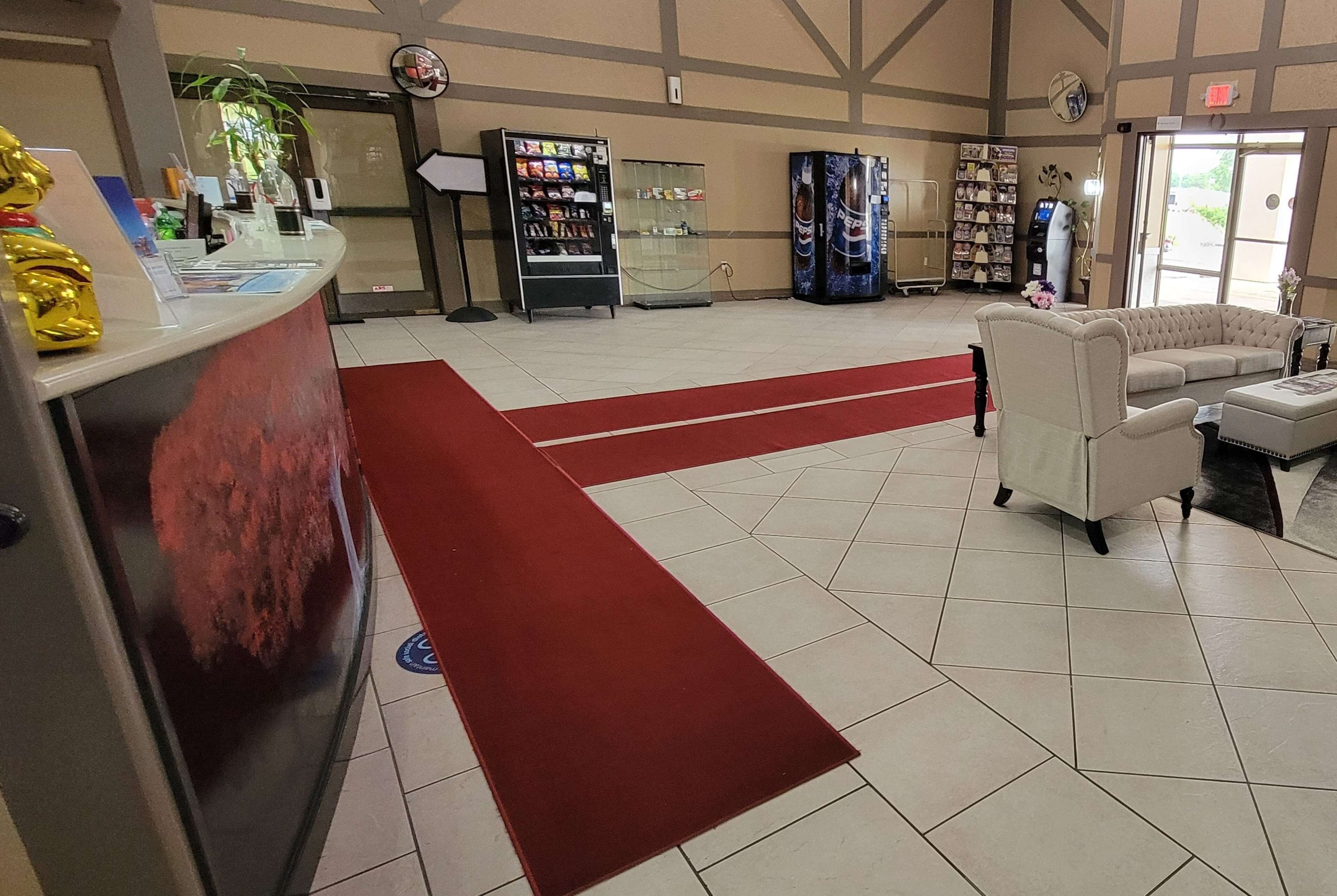 A reception area with a counter, vending machines, a sofa, and a red carpet.