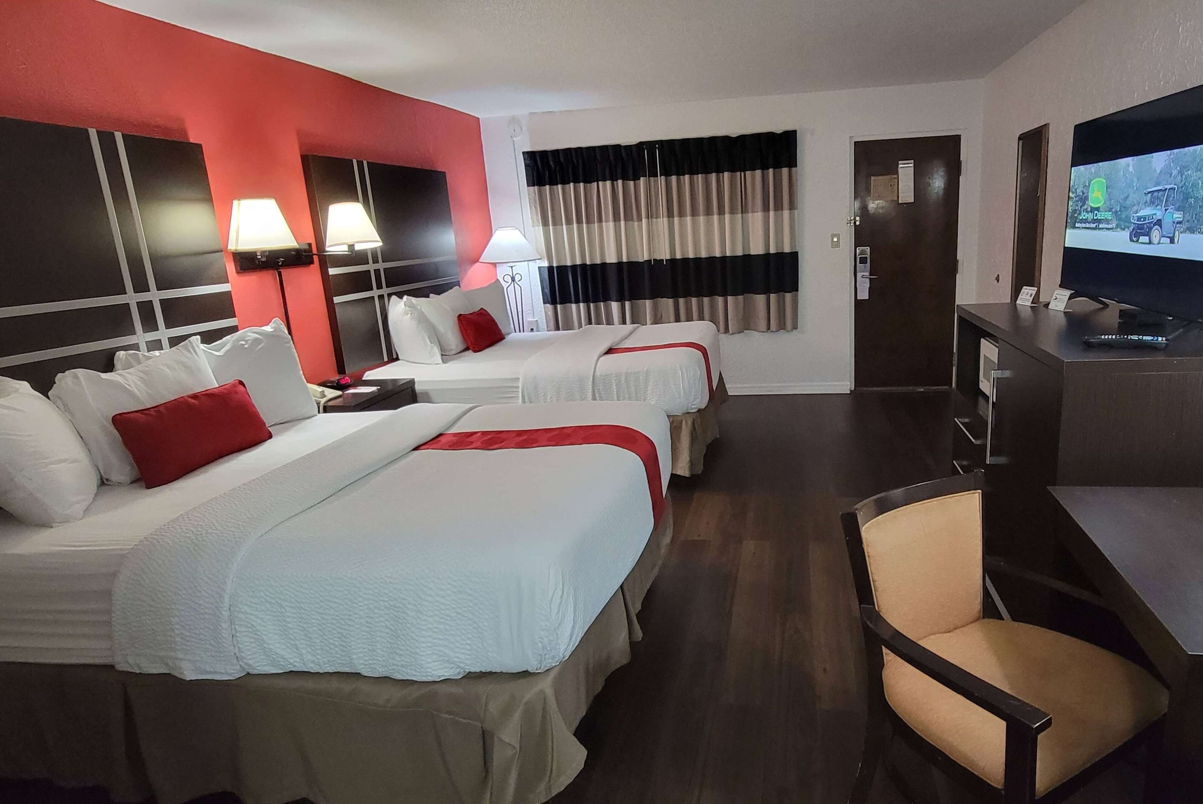 Habitación de hotel con dos camas, un televisor, un escritorio y una silla.