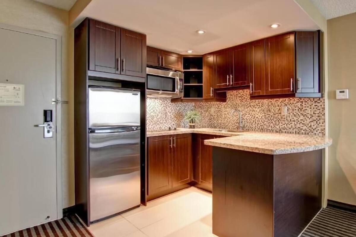 Una cocina moderna con armarios de madera, electrodomésticos de acero inoxidable y encimera de granito.