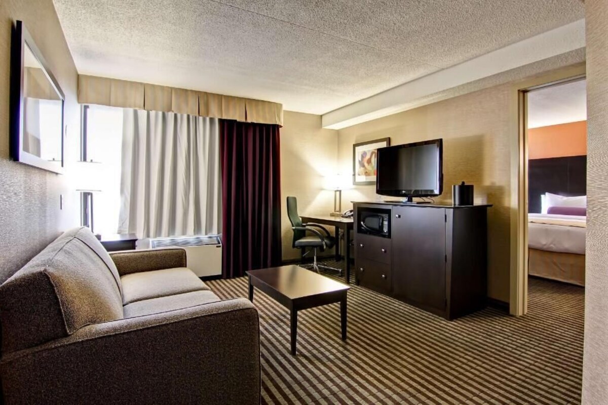 A hotel room with a sofa, a desk, a television, and a bed.