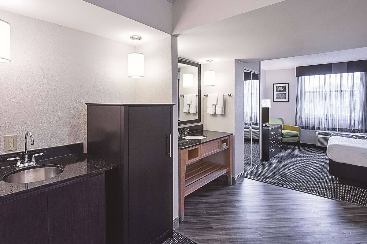 A hotel bathroom with a sink, mirror, and towel rack.