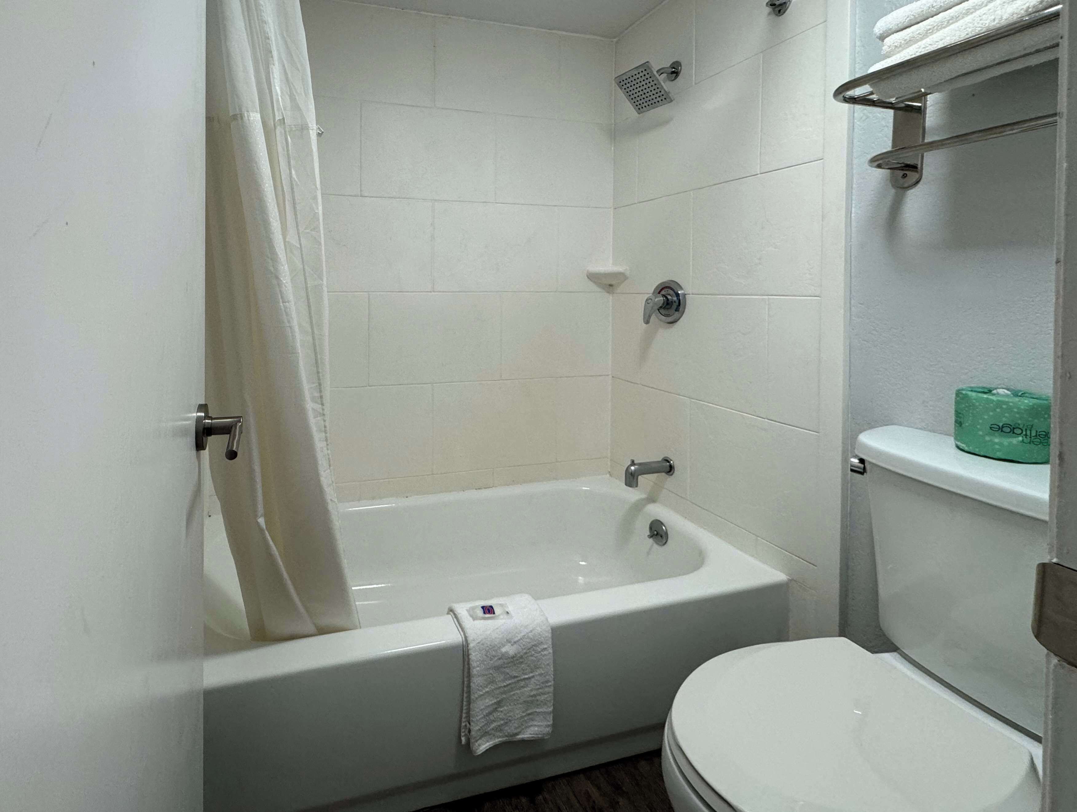 Une salle de bain avec une baignoire blanche, des toilettes et une pomme de douche.