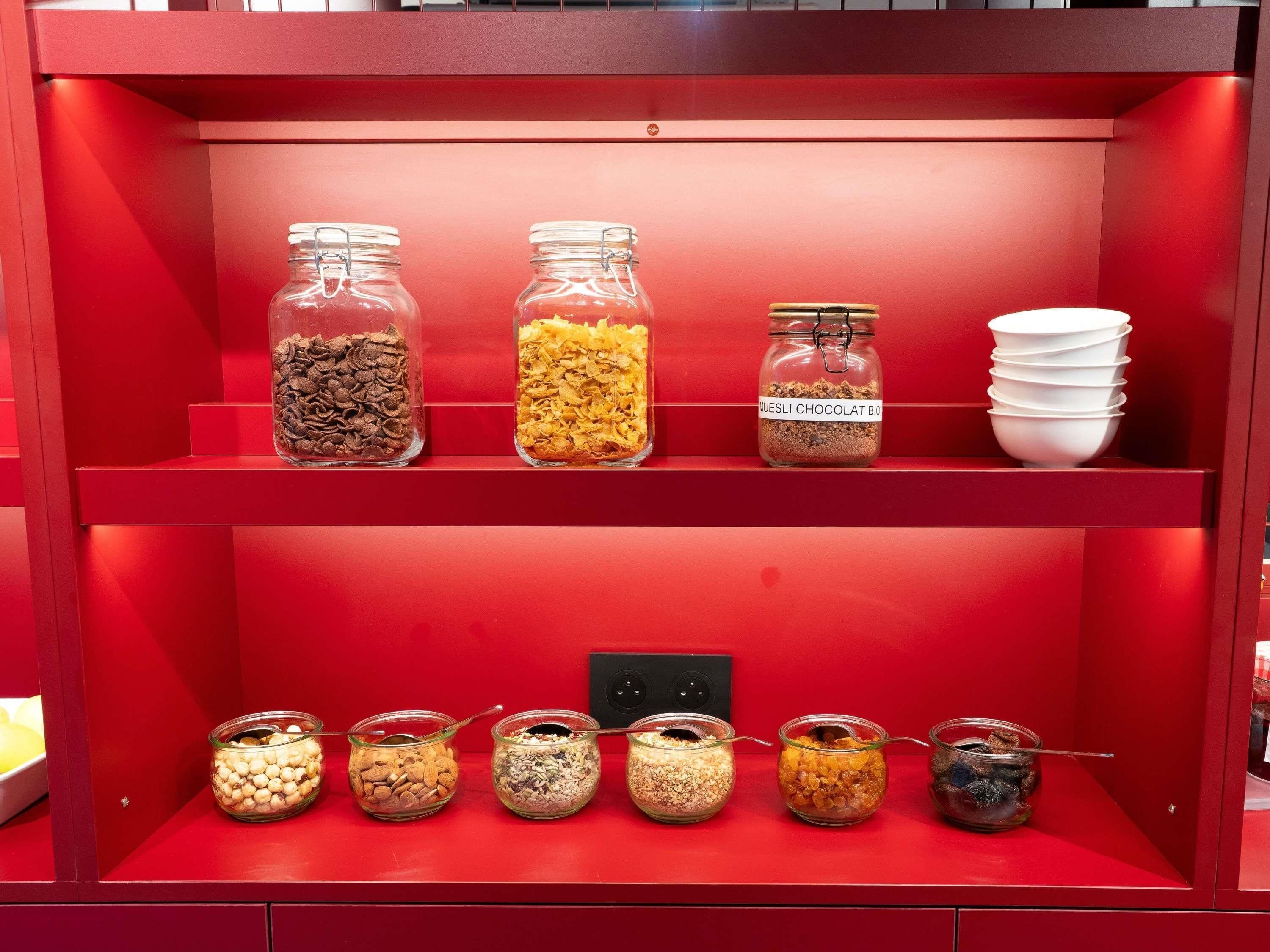Un estante rojo con varios frascos de vidrio que contienen diferentes alimentos.