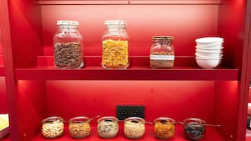 Un estante rojo con varios frascos de vidrio que contienen diferentes alimentos.