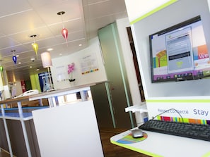 A hotel reception desk with a computer, a phone, and a sign that reads 'Stay connected.' - ibis Styles Bourg en Bresse Centre (Bourg-en-Bresse)