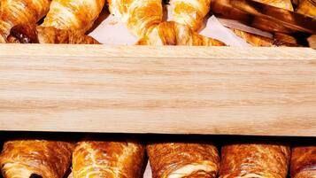 Variedad de pasteles, incluyendo croissants y medialunas de chocolate, expuestos sobre una superficie de madera.