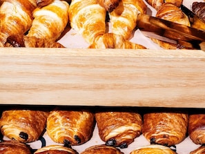 A variety of pastries, including croissants and chocolate-filled pastries, displayed on a wooden surface. - ibis Styles Bourg en Bresse Centre (Bourg-en-Bresse)