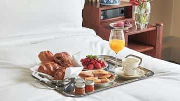 Una bandeja de desayuno bien dispuesta con pasteles, bayas y un vaso de jugo de naranja sobre una cama.