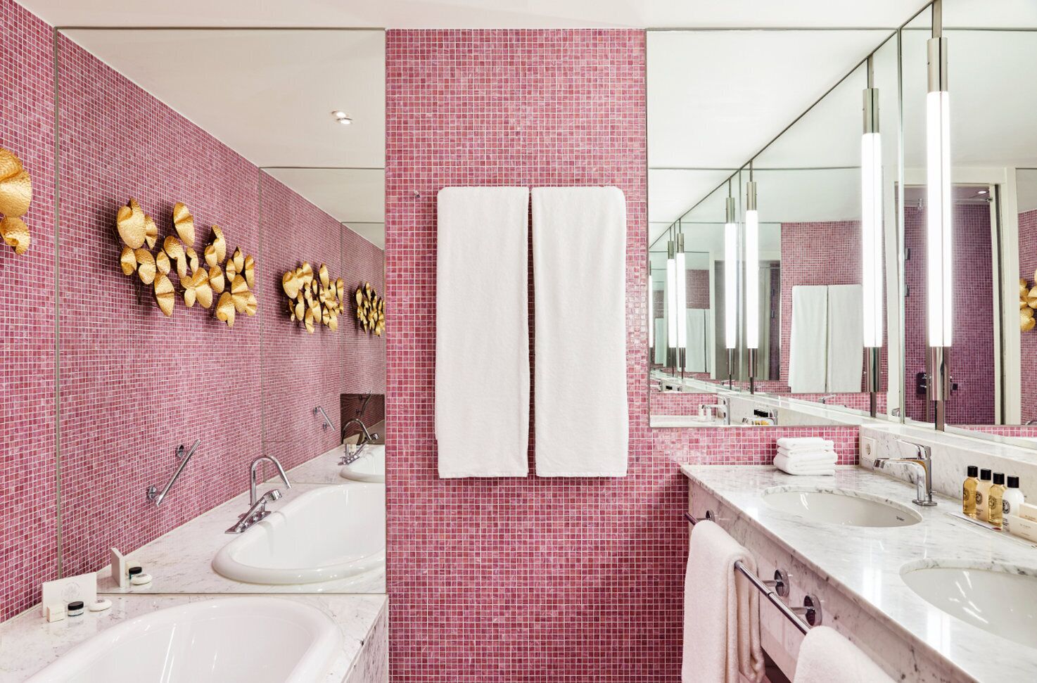 Ein modernes Badezimmer mit rosa Mosaikfliesen, zwei Waschbecken und einem großen Spiegel.