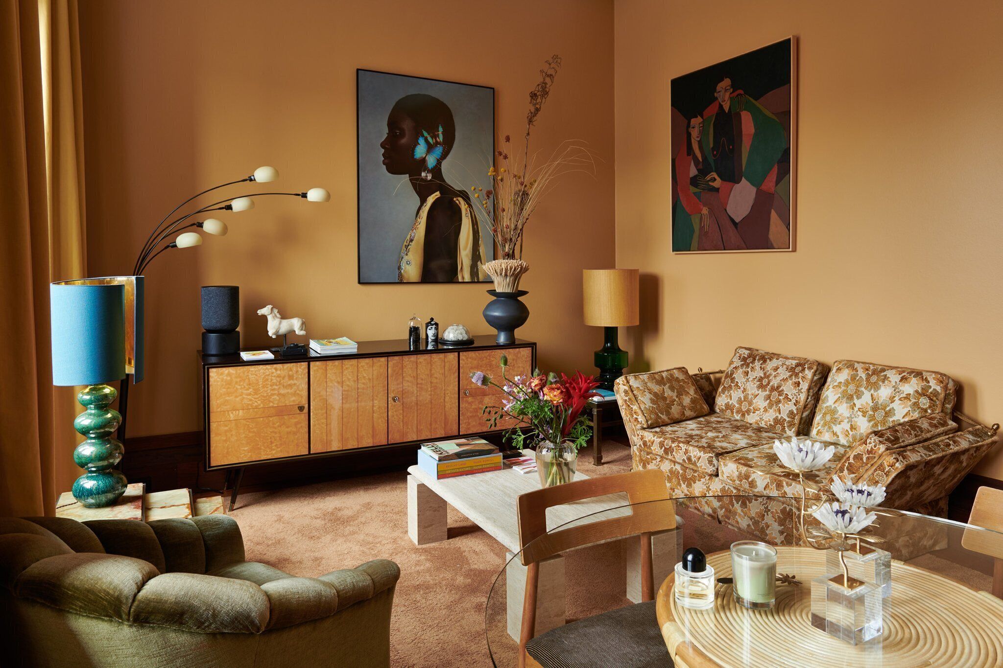 Una sala de estar con sofá, sillón, mesa de centro y aparador con objetos decorativos.