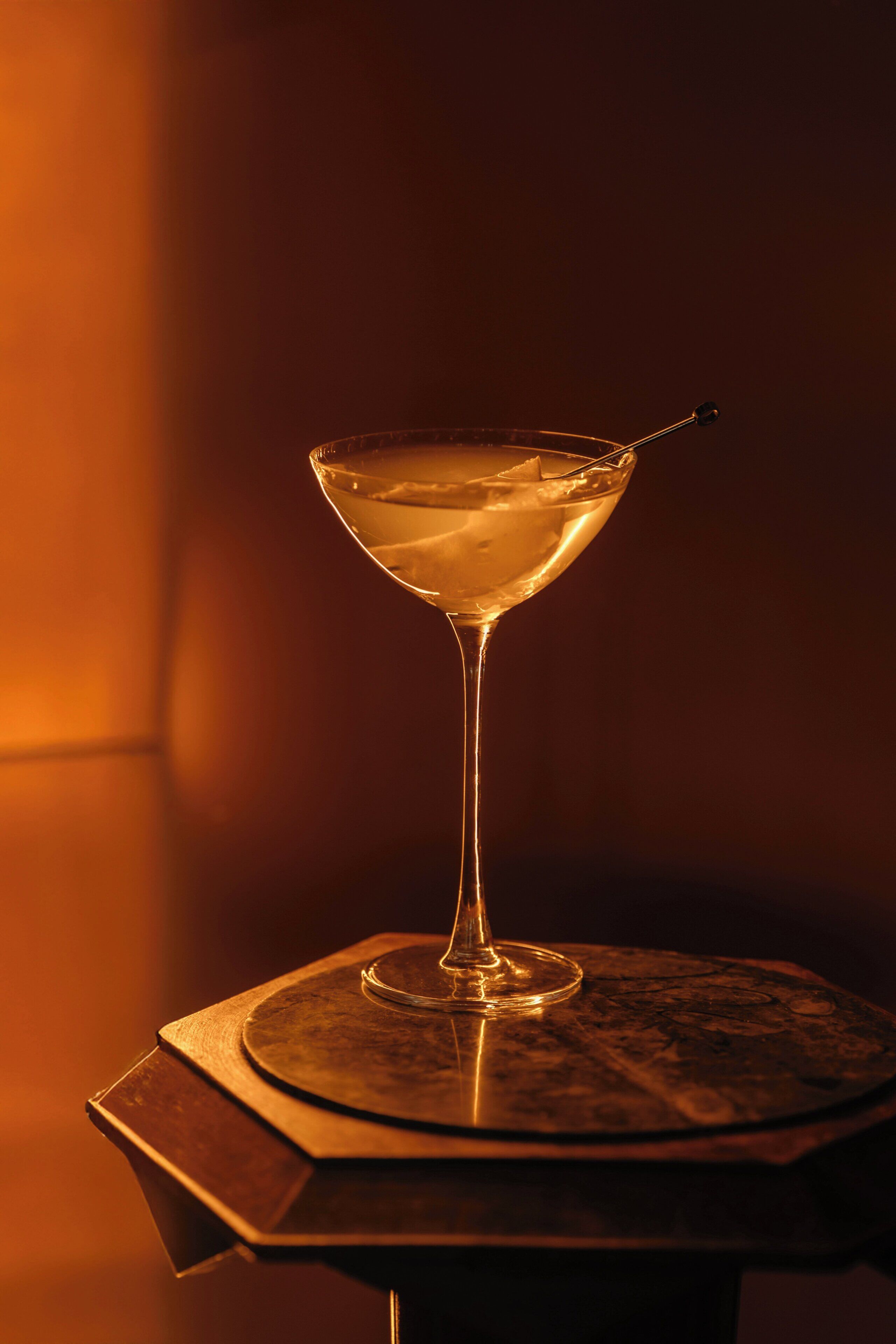 Ein Martini-Glas auf einem runden Tisch mit strukturierter Oberfläche.