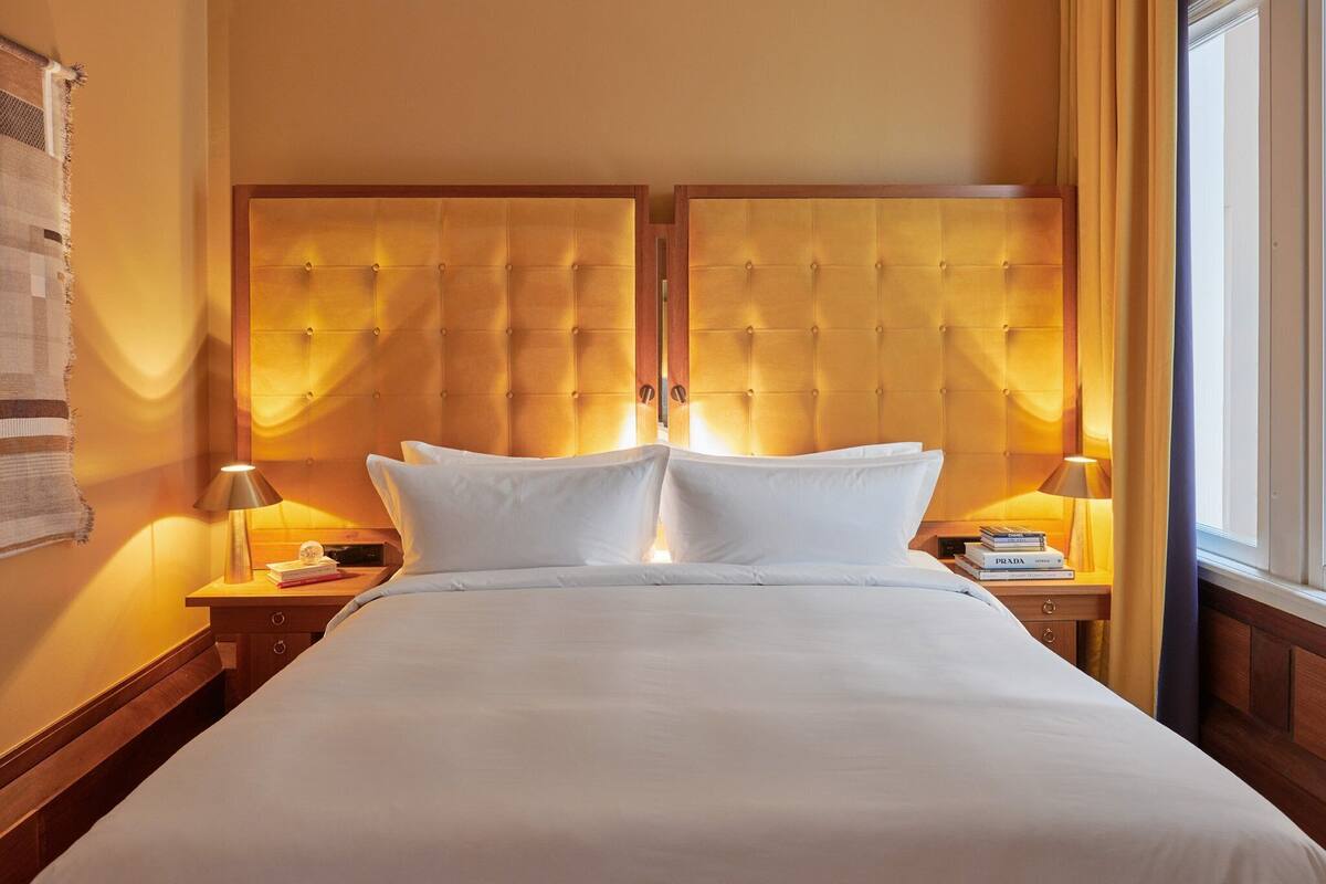 A hotel room with a large bed, two bedside tables, and a window with curtains.