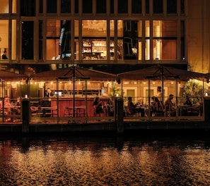 A waterfront restaurant with outdoor seating, a bar, and a view of the water. - De L'Europe Amsterdam (Amsterdam)