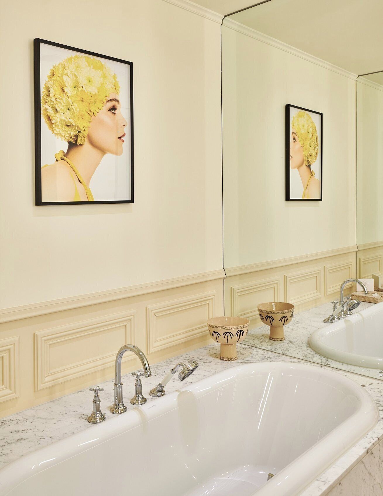 Un baño con dos lavamanos, un espejo grande y obras de arte enmarcadas en la pared.