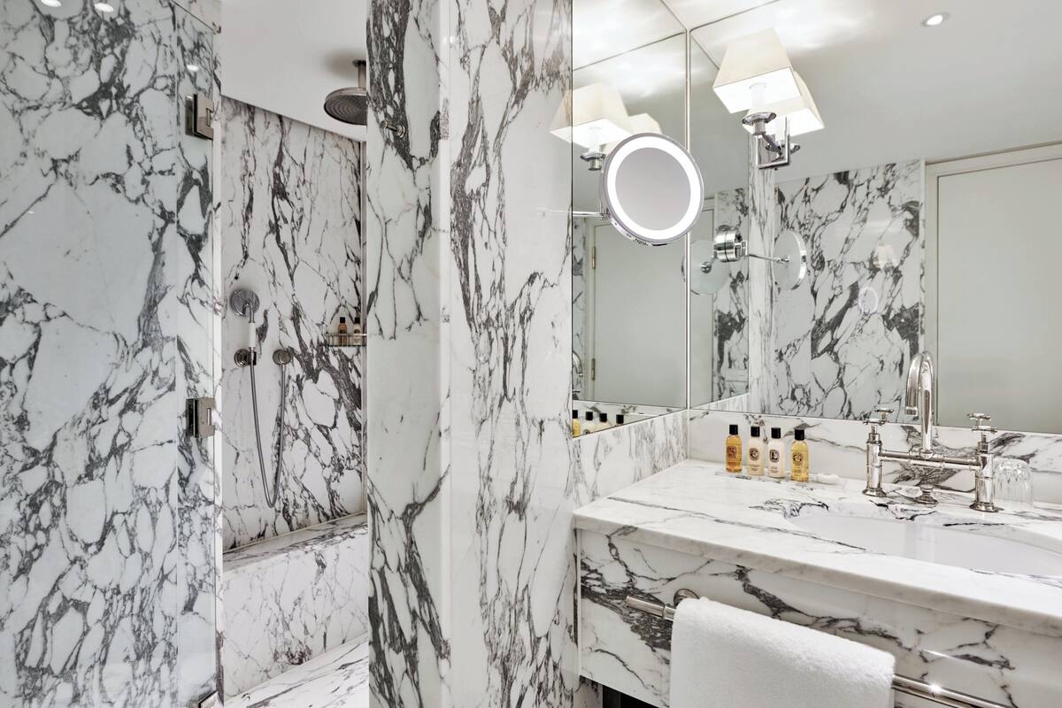 A bathroom with a marble vanity, a large mirror, and a ring light.