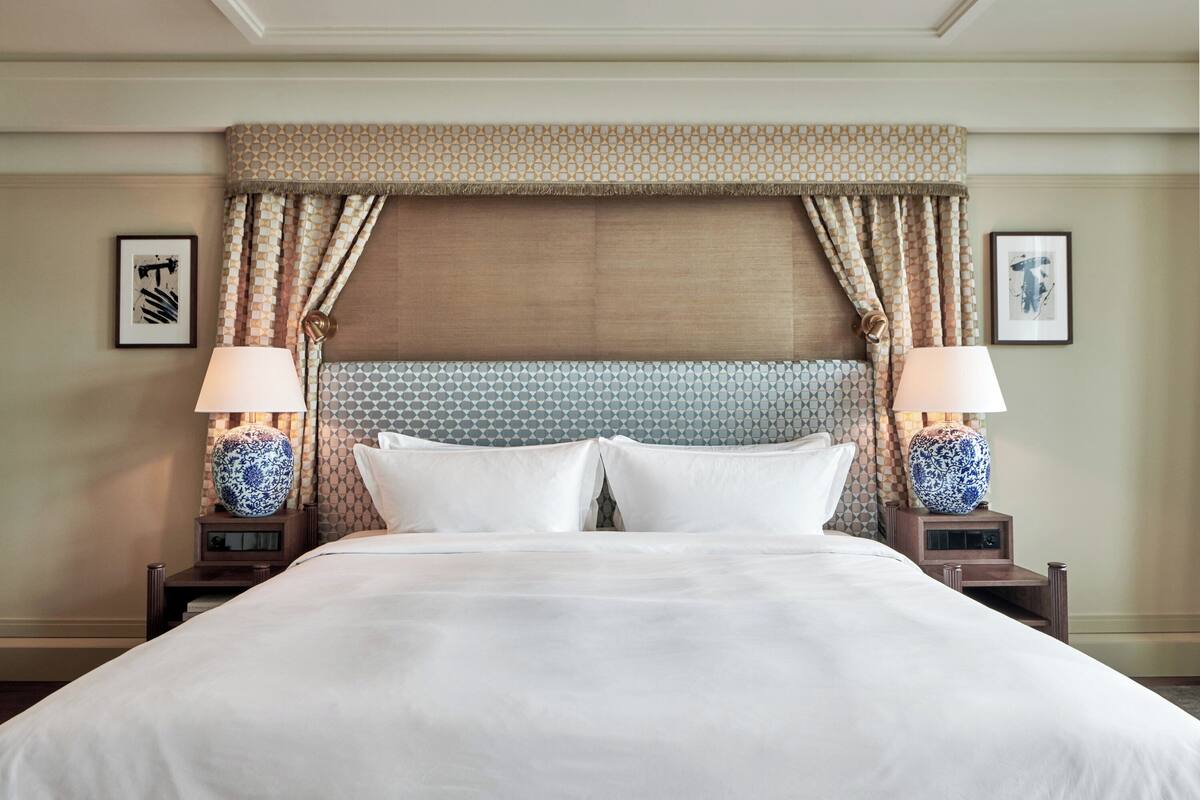 A neatly made bed with a patterned headboard, two bedside lamps, and framed artwork on the walls.