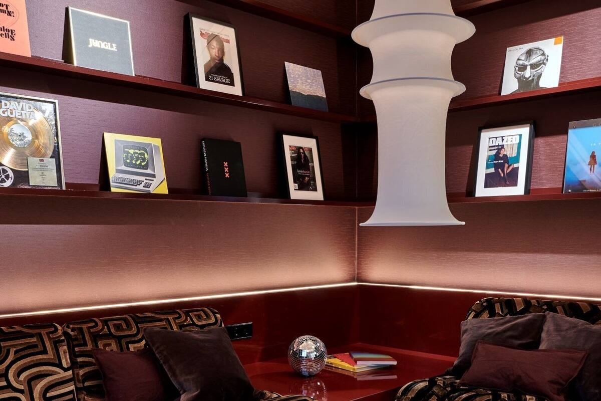 A cozy lounge area with patterned sofas, a central coffee table, and a bookshelf with various items.