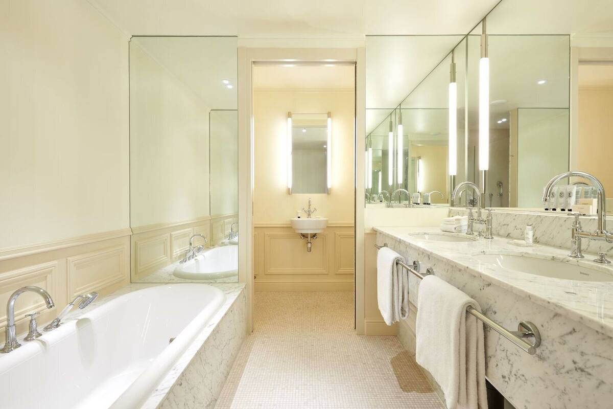 A modern bathroom with a large bathtub, two sinks, and a mirror.