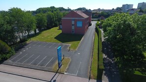 Un hôtel doté d’un parking, un bâtiment à la façade rouge et un espace verdoyant.