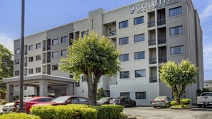 A modern hotel building with multiple floors, balconies, and a parking area with several cars. - Country Inn & Suites by Radisson, Atlanta Downtown (Atlanta)